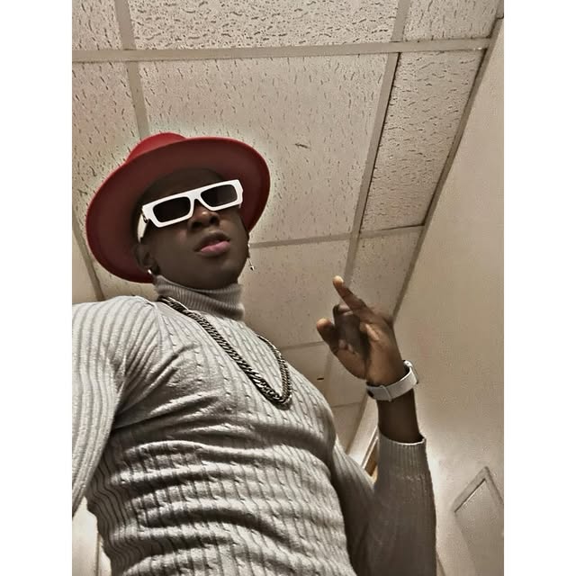 SECKY in a red hat, white sunglasses and knit, pointing up