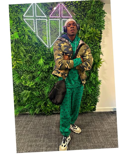 SECKY in a green camouflage tracksuit against a living wall